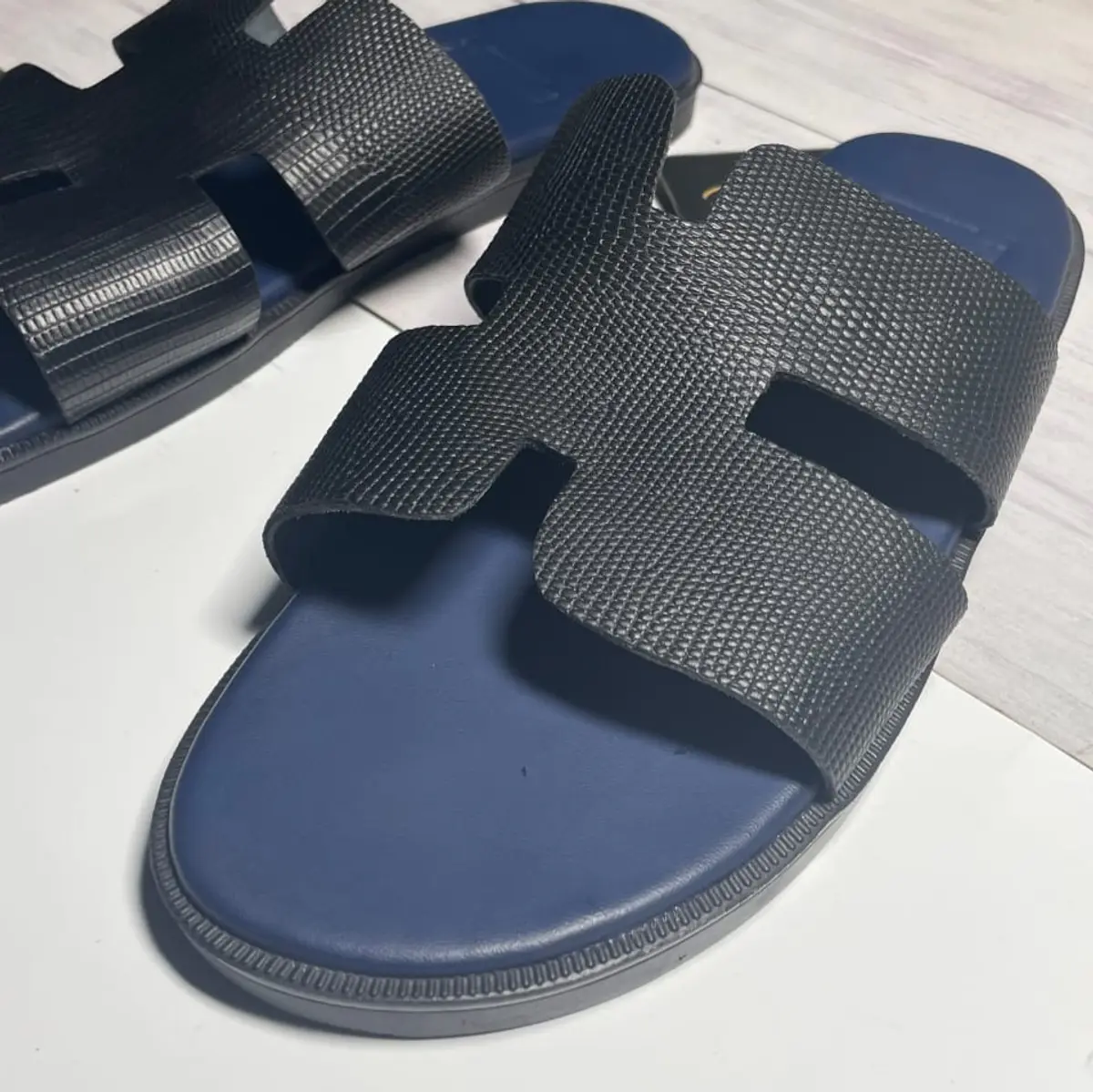 A side view of a leather black slippers with blue footbed