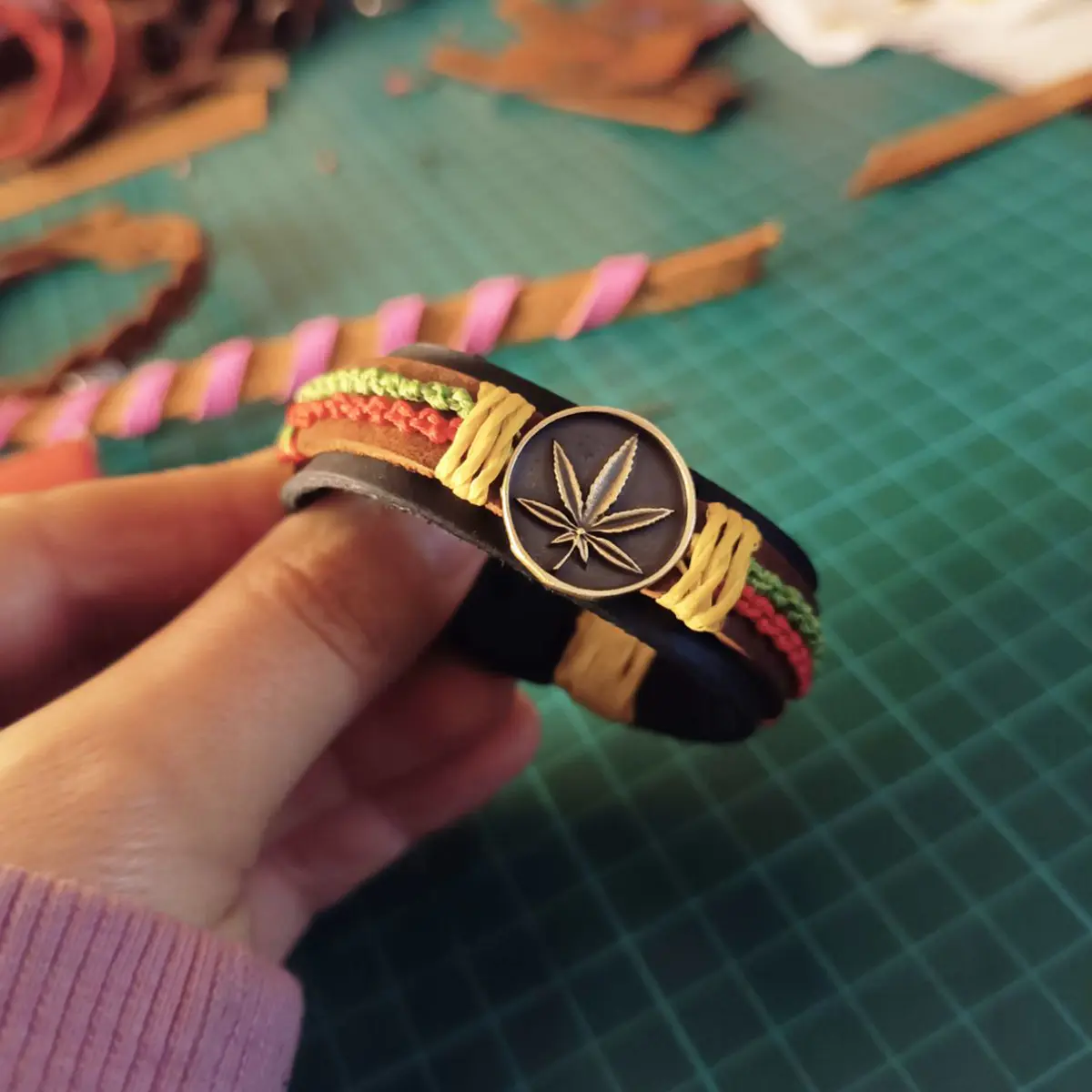 Handmade Rasta Leather Cuff Bracelet with leaf pendant and woven wax cords in Jamaican colors