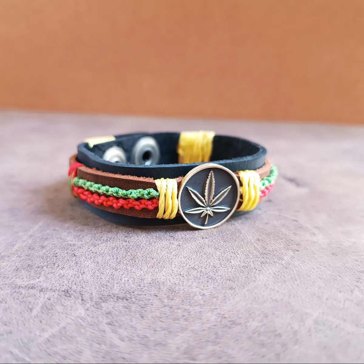 Handmade Rasta Leather Cuff Bracelet with leaf pendant and woven wax cords in Jamaican colors