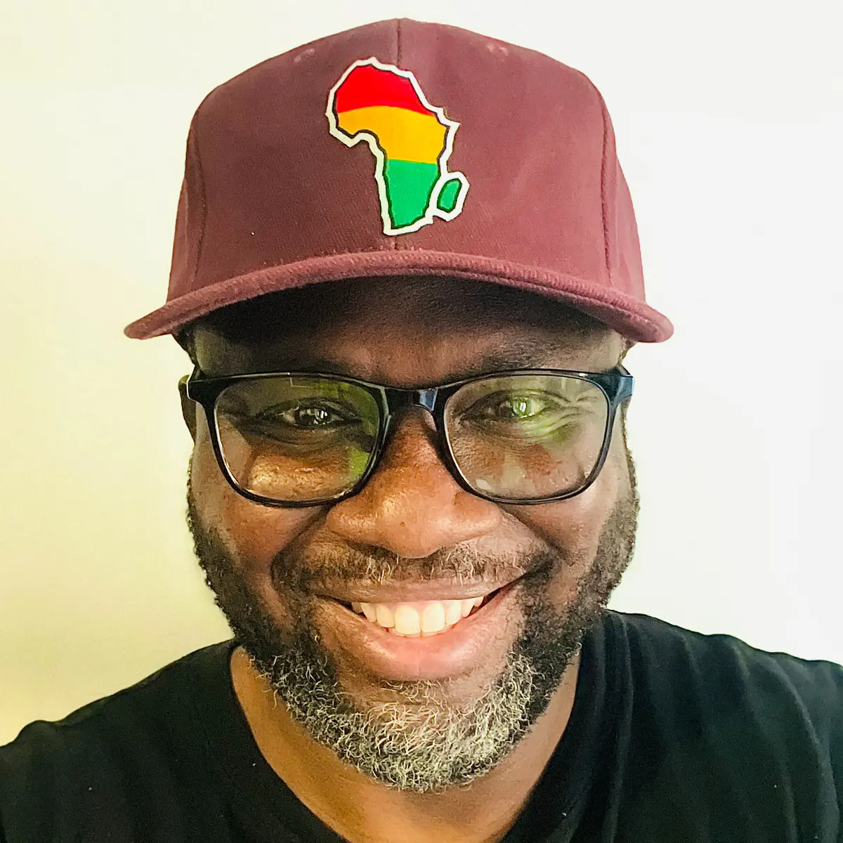 A black male wearing a burgundy baseball cap with the African map logo