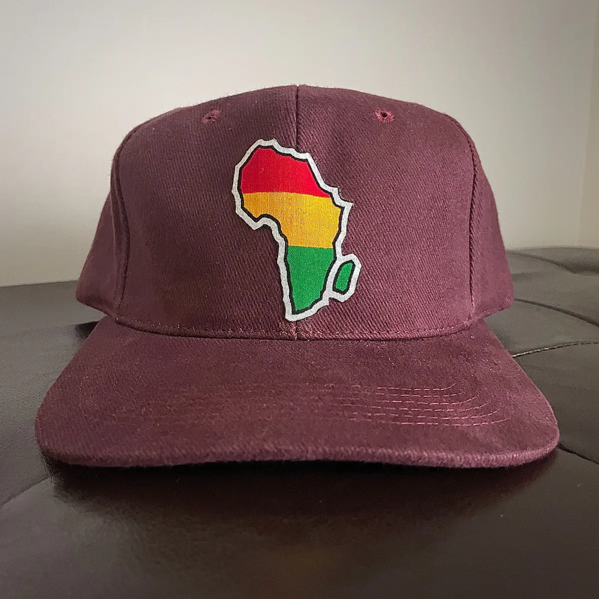 A burgundy baseball cap with the African map logo