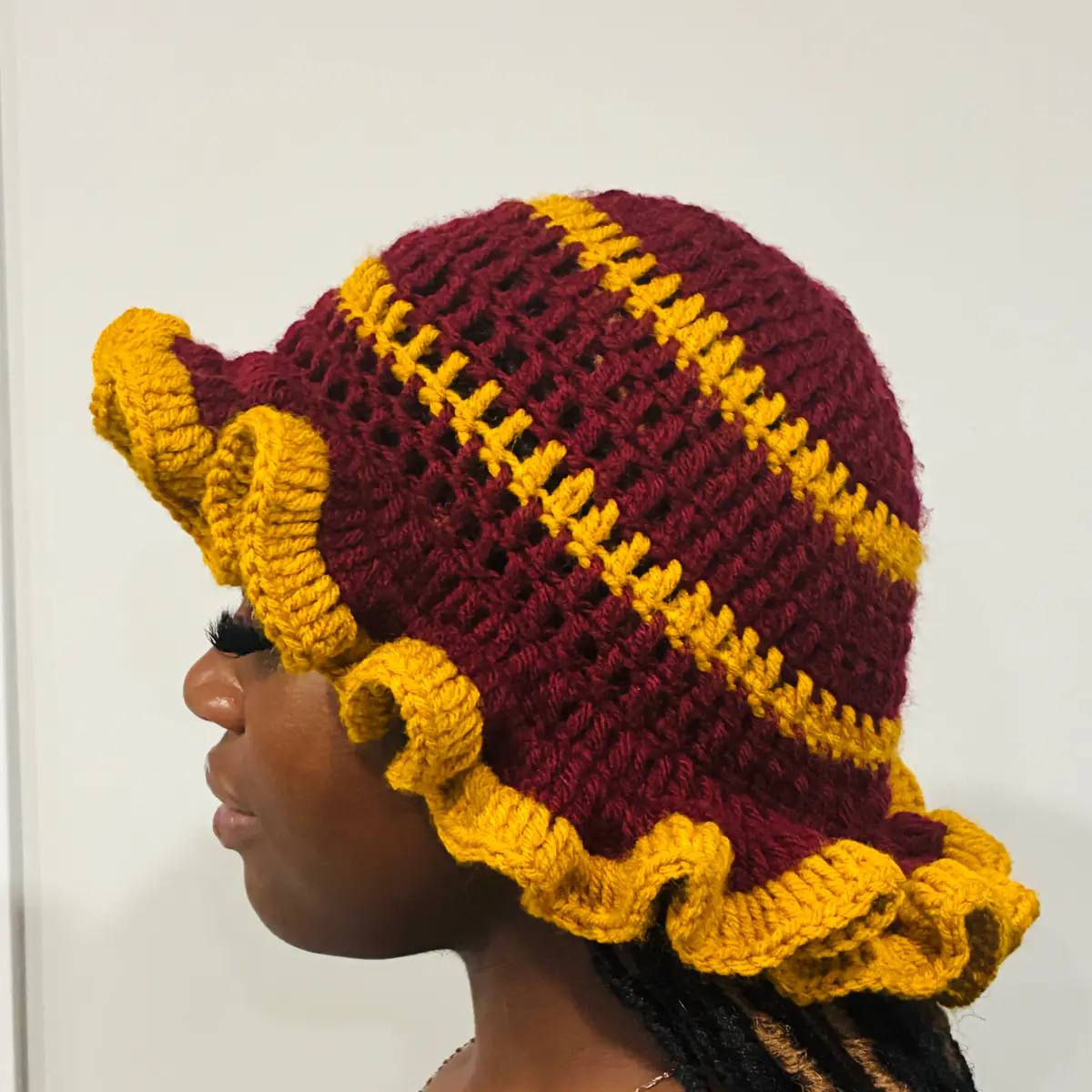 Sideview of a Burgundy & Mustard yellow crochet ruffled cap