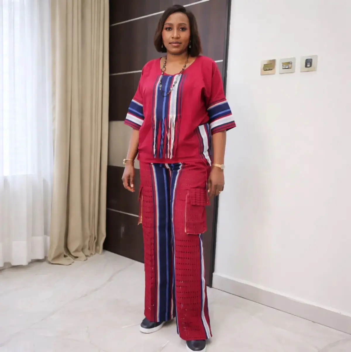 Red and navy striped Aso Oke women’s two-piece set with fringe-detail top and wide-leg pants.