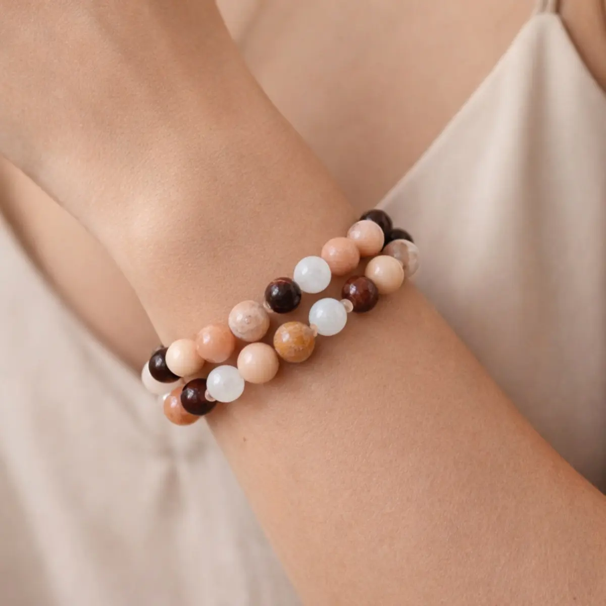Handmade natural gemstone bracelet pair with peach, white, and brown beads styled on a woman’s wrist.
