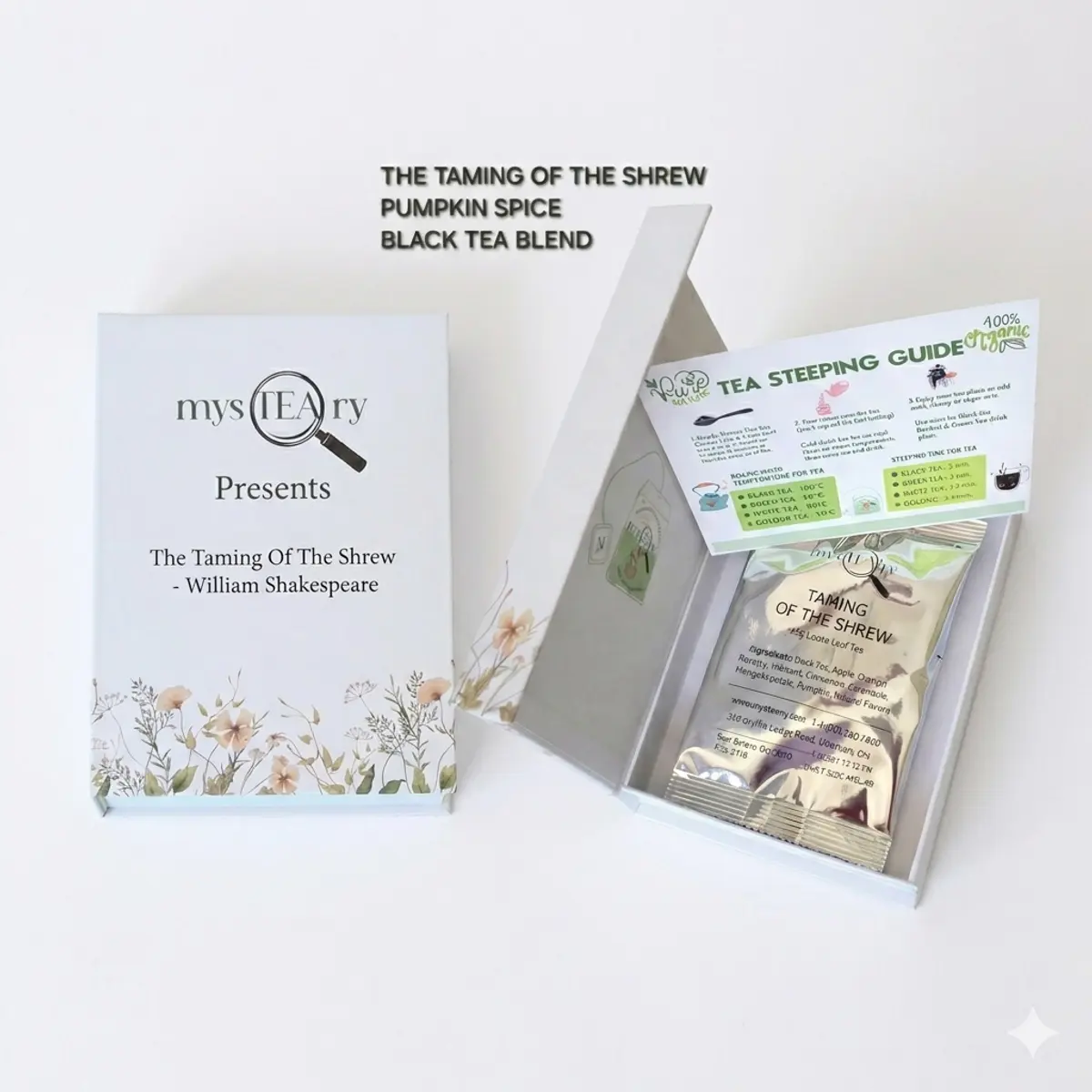 A white book-style gift box for 'The Taming of the Shrew – Pumpkin Spice Black Tea Blend' by mysTEAry, shown both closed and open. The open box reveals a silver foil pouch of loose-leaf tea and a green and white Tea Steeping Guide card with floral detailing. Color: White, Silver, Green