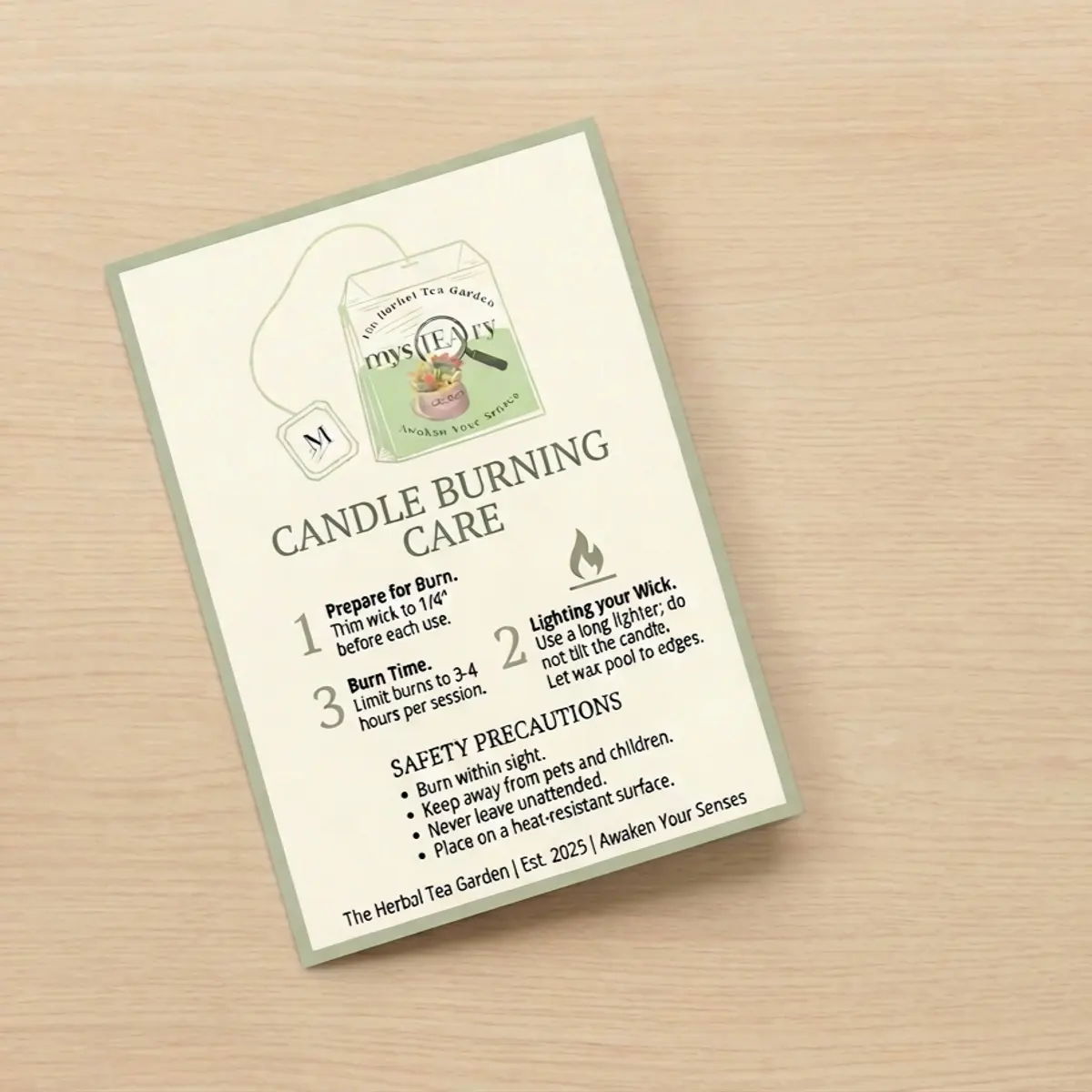 A printed candle burning care card from The Herbal Tea Garden laid flat on a light wood surface, detailing wick trimming instructions, burn time guidance of 3 to 4 hours per session, and safety precautions including keeping away from pets and children. Color: Cream and Sage Green